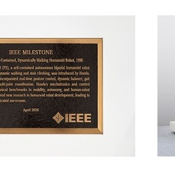 IEEEマイルストーン銘板（左）と人間型自立二足歩行ロボットP2（右）