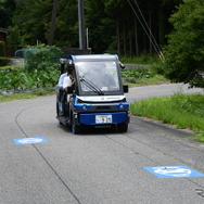 市道を走る「奥永源寺けい流カー」。道路上の黒い線が自動運転を制御するために敷設された電磁誘導線