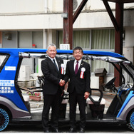 「奥永源寺けい流カー」の前で握手を交わす小椋正清市長（右）とブリヂストンの蓮沼 利幸氏（左）