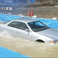 JAFのYouTube動画『冠水路走行テスト～セダンタイプ～』の1シーン。水深60cmの冠水路を時速10kmで走行しているところ。